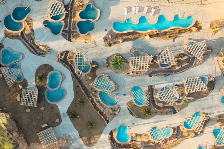 Aerial view of resort pools with winding shapes and surrounding lounge areas.